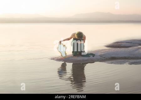 vain woman looks for her image in a mirror in a fantastic lake panorama Stock Photo