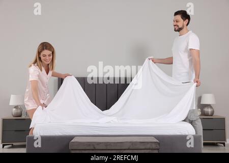 Couple changing bed linens in room. Domestic chores Stock Photo