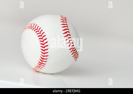 Closeup of a white baseball ball with red stitches on a white background Stock Photo