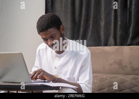 Working with papers. Serious african male entrepreneur work at home office alone hold read document hardcopy think on conditions terms. Focused young Stock Photo