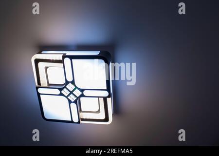Modern LED Ceiling Chandelier with Control Panel. Adjusting the Brightness of Lighting in the Room, Technology. Sleep Timer. Stock Photo