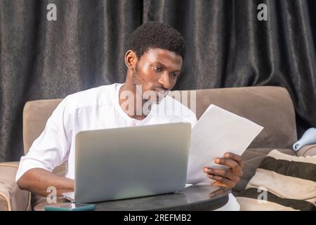 Satisfied smiling business man doing paperwork at home workplace. Entrepreneur reading financial reports, reading documents. Tenant making payment for Stock Photo