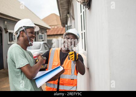 two cheerful african repair men shake hands Stock Photo