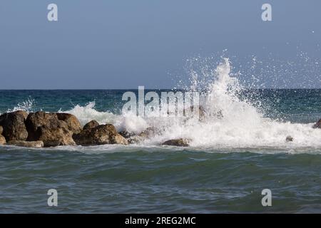 Wave breaking on rocks with the horizon in the background Stock Photo