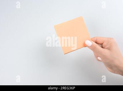 Blank sheet for notes. female hand holding note paper mockup for making note. blank reminder or paper notes above white background. copy space Stock Photo