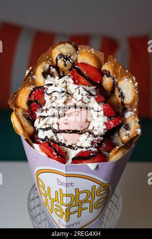 Bubble waffle topped with strawberry ice cream and sliced strawberries. Stock Photo