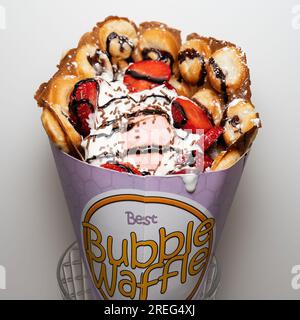 Bubble waffle topped with strawberry ice cream and sliced strawberries. Stock Photo