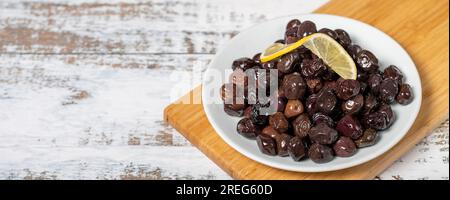 Black olive. Fermented olives and lemon slice in plate. Mediterranean flavors. Copy space. Empty space for text Stock Photo