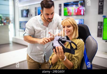 Couple enjoying with VR goggles at tech store. Shopping couple having fun at marketplace. Stock Photo