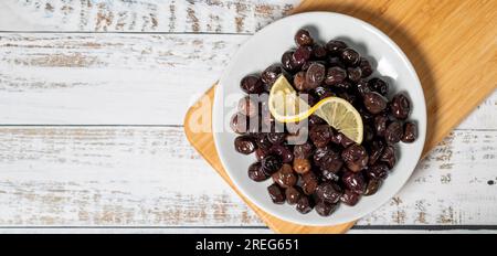 Black olive. Fermented olives and lemon slice in plate. Mediterranean flavors. Top view. Copy space. Empty space for text Stock Photo