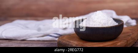 Coconut powder. Grounded coconut flakes on wood floor. Dark bowl of dessicated coconut. Copy space. Empty space for text. Copy space. Empty space for Stock Photo