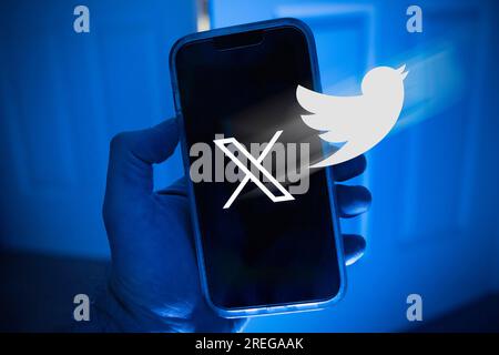 Mobile phone in one hand with the symbol X, the new name of the former app Twitter Stock Photo