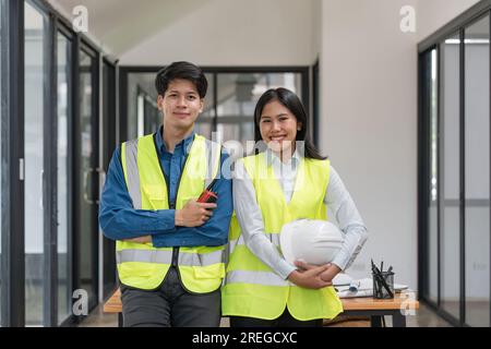 Two engineer workers stand and look at camera with smiling and arm crossed on office of construction Stock Photo