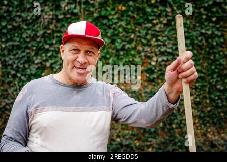 Portrait of a senior man in a ball cap with toothy grin doing yardwork Stock Photo