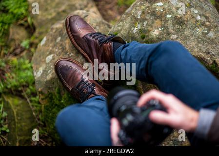 Detail of person wearing leather boots sitting on stone Stock Photo
