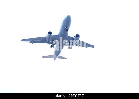 Low angle view of commercial airplane flying in sky with landing gear ready to take off at airport Stock Photo