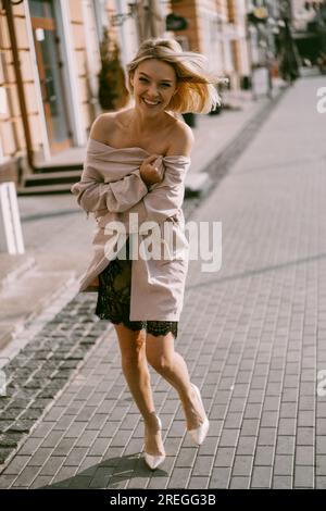 Beautiful blonde woman in a lace dress on a city street, happy smile. Stock Photo