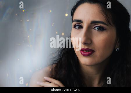 Close-up of a girl on a gray background with twinkle lights Stock Photo