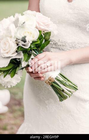 Close up of wedding bands on bride's hand while holding bouquet Stock Photo