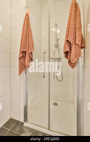 Staging modern bathroom with two decorated brown hand and body towels  hanging on rack by shower in model home, apartment or house Stock Photo -  Alamy