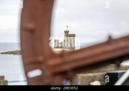 The Castle of Refuge on St Mary's Island, Douglas Bay harbour, Isle of Man, viewed through recovered old iron wheel from the cable tramway machinery Stock Photo