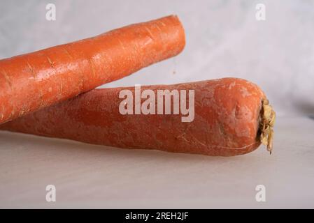 Carrots being Sliced on White Cutting Board With Chef's Knife and Wood Stand Stock Photo
