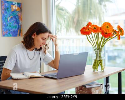 Mad young woman worker losing job result on broken pc, low internet connection, working remotely at home. Stressed attractive lady annoyed by hard wor Stock Photo