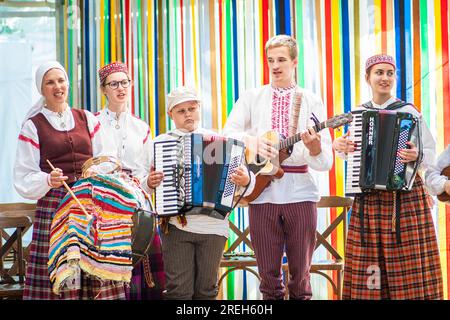 Group of adults and children in traditional clothes playing and singing on the stage during XXVII Nationwide Latvian Song and XVII Dance Festival Stock Photo