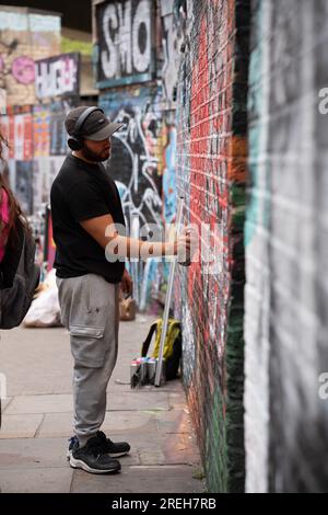 Graffiti artsist pray painting on a wall in Brick Lane, London, England. Stock Photo