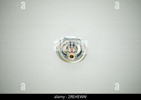 Sprinkler mounted on the ceiling with a white background. Close-up. Stock Photo
