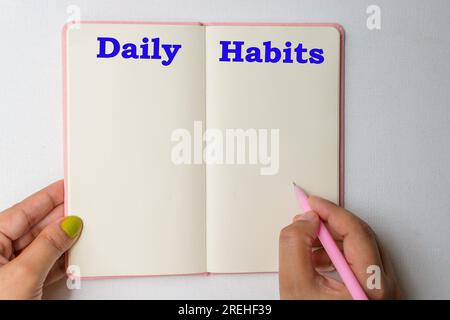 Diary in hand . Daily Habits text or word written on it. Stock Photo