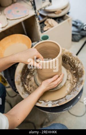 High angle view of female artisan making clay vase on pottery wheel in ceramic workshop Stock Photo