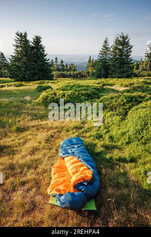 Open sleeping bag on mat at mountains. Bivouac and camping outdoors under clear sky Stock Photo