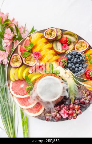 Raw fruits and berries assortment platter on the plate, on the white table Stock Photo