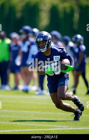 Seattle Seahawks players, including running back Kenny McIntosh (25) and  wide receiver Tyjon Lindsey (81), run onto the field for warmups before the  NFL football team's mock game, Friday, Aug. 4, 2023