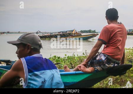 Binangonan, Philippines. 28th July, 2023. Residents nearby watches the capsized motorized boat named Princess Aya in Laguna Lake. A motorized boat named Princess Aya was capsized during the mid-day of July 27, 2023 due to a strong wind of Typhoon Doksuri and Southwest Monsoon in Binangonan. The passenger boat carried an estimate of 70 passengers, 40 of them survived and 26 passengers were pronounced dead. According to the investigation, and the Philippine Coast Guard said that the motorized boat can only take a maximum of 42 passengers, the captain and crew members. The retrieval operation for Stock Photo
