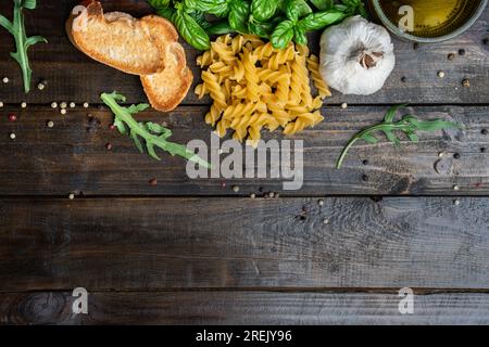 Italian food ingredients, fresh mozzarella, bruschetta, raw tagliatelle, and basil leaves on a dark wooden background Stock Photo