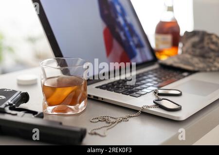 Whiskey with ice in a glass and a flask. Nearby is a laptop. Rest of the day off. Stock Photo