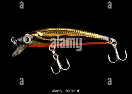 Yellow and black minnow plastic fishing lure isolated on black background Stock Photo