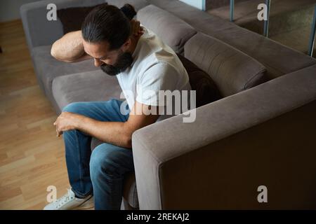 Bearded man is holding on to his sore neck Stock Photo