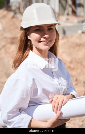 Portrait of beautiful woman architect in hardhat standing at construction site Stock Photo