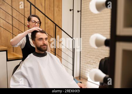 Cute barber is working with a client in modern barbershop Stock Photo