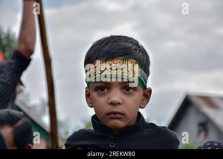 Srinagar, India. 28th July, 2023. A young Shiite Muslim mourner looks on as he attends a Muharram procession in Srinagar. Muharram is a month of mourning in remembrance of the martyrdom of Imam Hussain, the grandson of Prophet Muhammad (PBUH). Credit: SOPA Images Limited/Alamy Live News Stock Photo