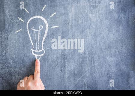 Finger pointing light bulb drawn with chalk chalkboard. Beautiful photo Stock Photo