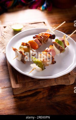 Homemade Skewers with meat and grilled vegetables served on a rustic wooden board, also known as brochettes, alambre, chuzo or pincho. Stock Photo