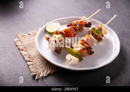 Homemade Skewers with meat and grilled vegetables served on a rustic wooden board, also known as brochettes, alambre, chuzo or pincho. Stock Photo