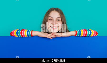 laughing child behind blank blue paper with copy space for advertisement Stock Photo