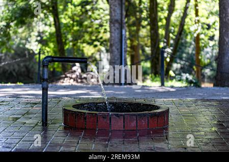 Prattville, Alabama, USA-June 16:2023: Flowing water in the Doster Road Artesian Well House, a public well where people can get water. Stock Photo