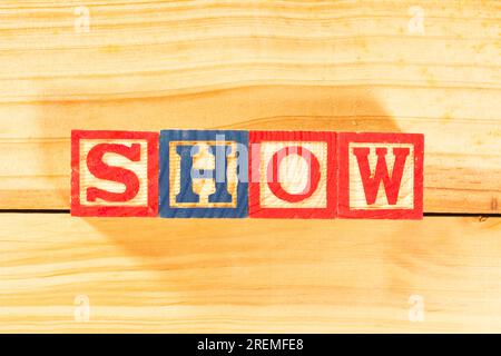 Spectacular colorful letters on wooden cubes on a wooden board with the word SHOW. Stock Photo