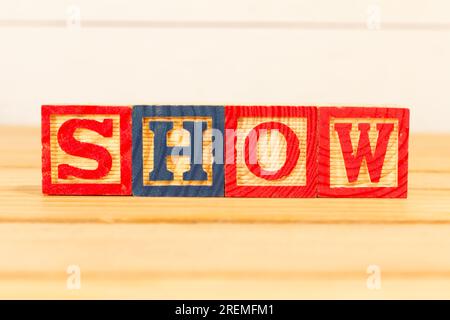 Spectacular colorful letters on wooden cubes on a wooden board with the word SHOW. Stock Photo